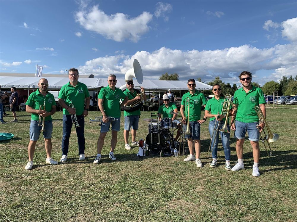 Les huit musiciens du Roue Libre Brass, polos verts et cuivres à la main